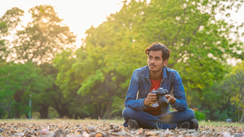 a man sitting on the ground holding a cup and looking at the camera