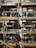 A collection of vintage sewing machines displayed on wooden shelves against a brick wall. The sewing machines are intricately designed with ornate patterns, and the shelves are supported by metal pipes. The lighting casts shadows on the wall, adding depth to the display.