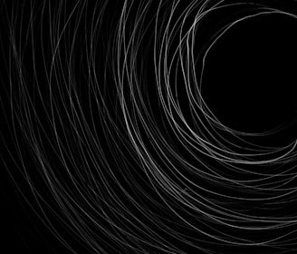 A series of swirling, thin, white lines create a spiral pattern against a black background, converging into a central dark void.