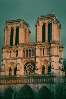 a large building with a clock on it with Notre Dame de Paris in the background