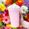 a hand holding a plastic cup with a pink substance in it