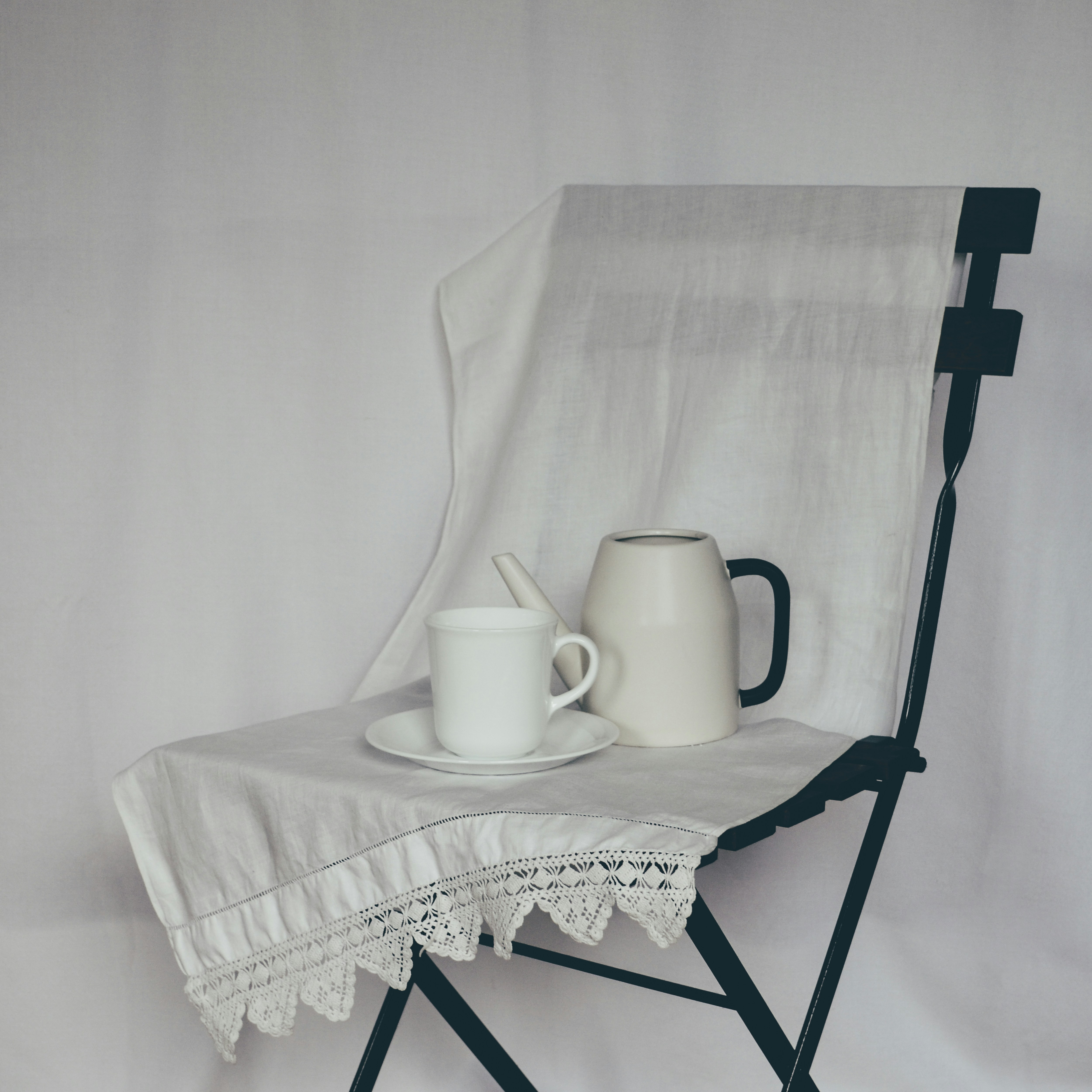 a white table with a white cloth and a white teapot on it
