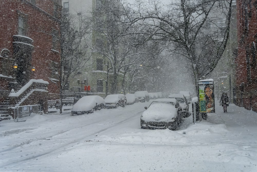 a snowy street with cars parked on the side
