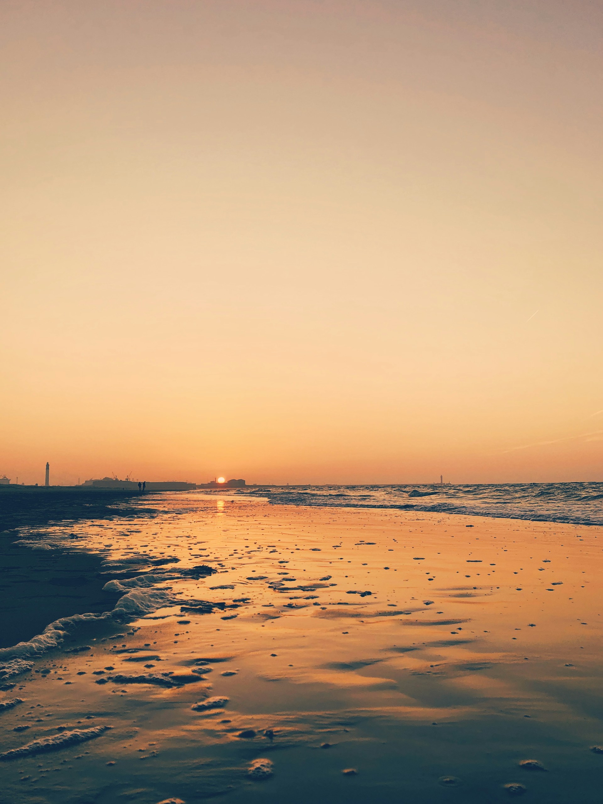 a beach with a body of water and a tower in the distance