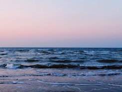 A serene ocean view at dawn with gentle waves reflecting soft pastel colors.