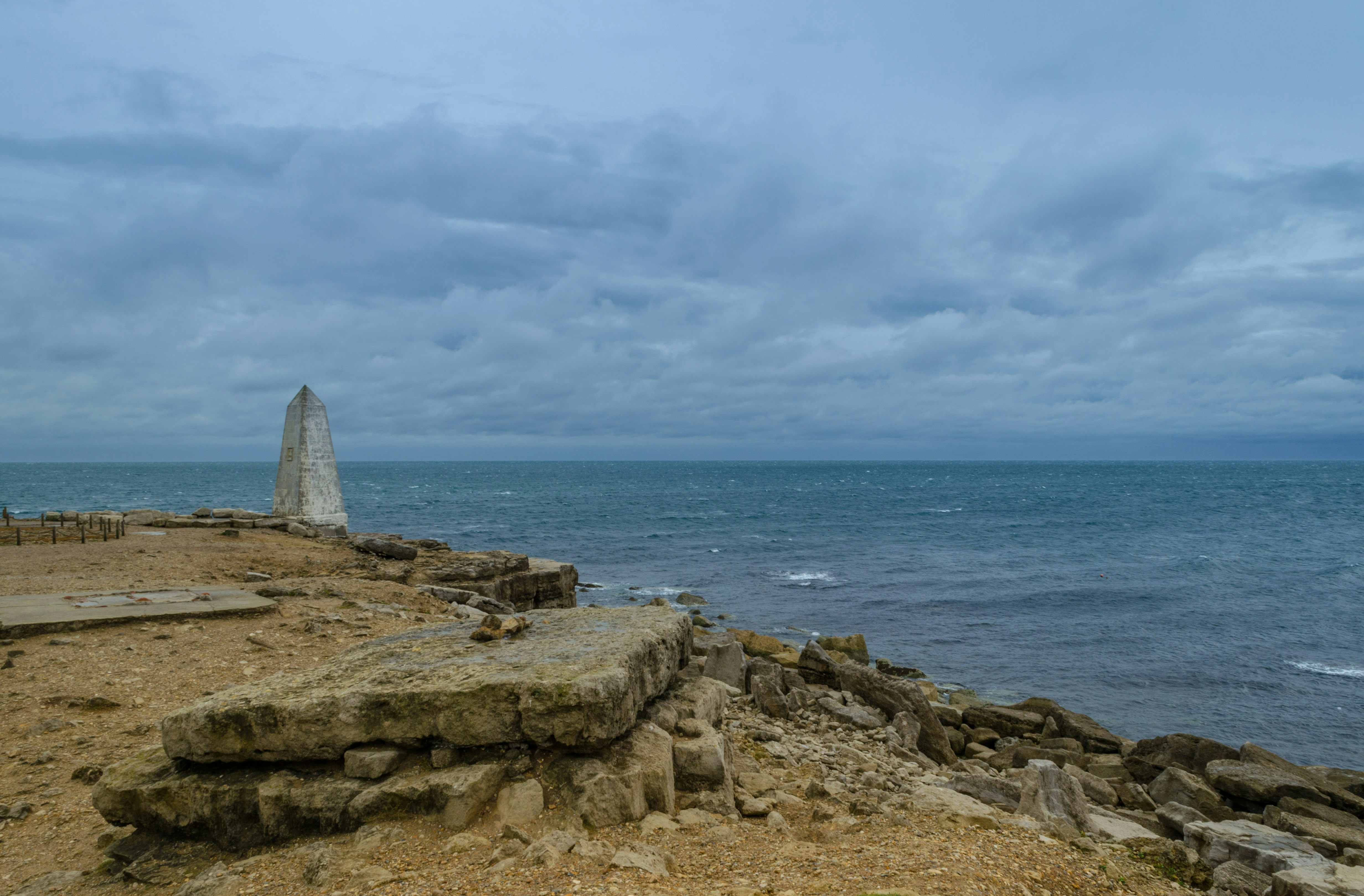 a rocky beach with a large rock structure in the distance