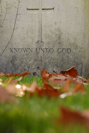 A weathered stone monument engraved with symbols of faith and English heritage.