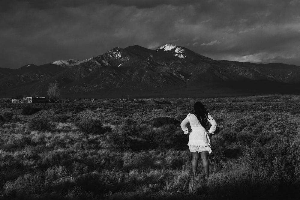 a person standing in a field with a mountain in the background