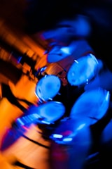 A dynamic abstract image of a drum set in blurred motion with vibrant blue and orange lighting, creating a sense of energy and movement.