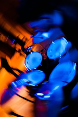 A dynamic abstract image of a drum set in blurred motion with vibrant blue and orange lighting, creating a sense of energy and movement.