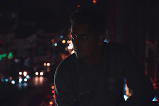 Man looking thoughtfully at a glowing futuristic city skyline at night.