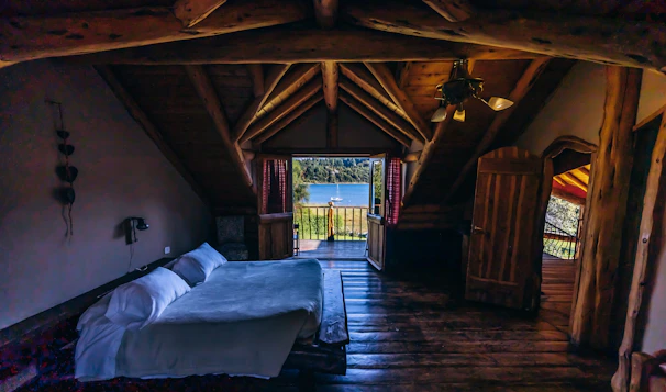 Cozy rustic cabin room with wooden walls and a large window showing a forest view