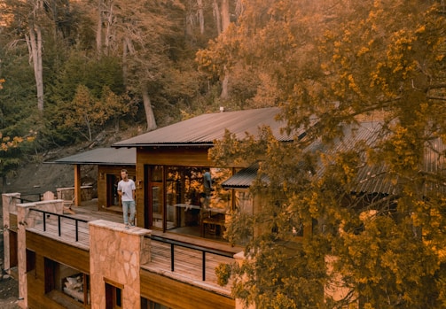 Cozy luxury suite balcony overlooking lush green forest under a soft golden sunset.