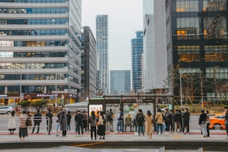 A modern city bus stopping at a bustling urban bus stop filled with waiting passengers.