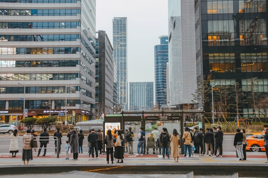 A modern city bus stopping at a bustling urban bus stop filled with waiting passengers.