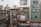 An old pharmacy with wooden display cabinets filled with various bottles and containers. A mannequin wearing a white lab coat stands behind the counter. Several framed photographs and vintage advertisements adorn the walls. The atmosphere invokes a sense of nostalgia and history.
