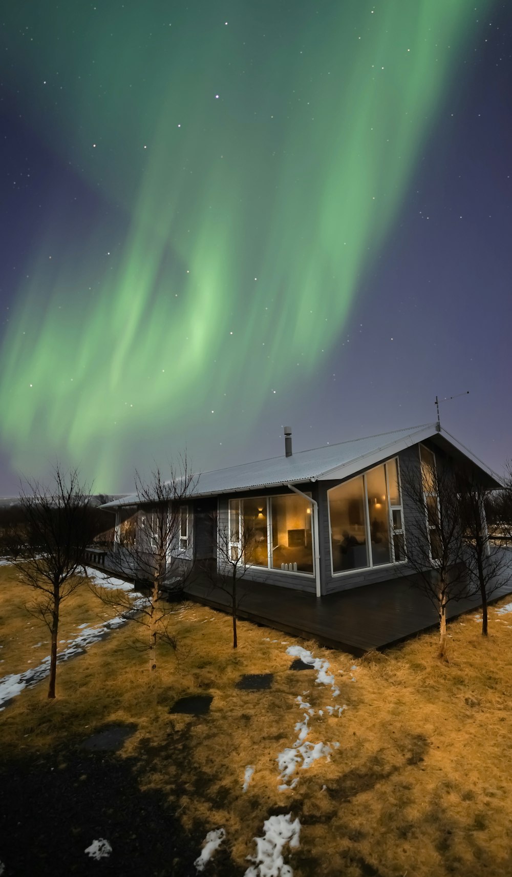a house with a green aurora in the sky above it