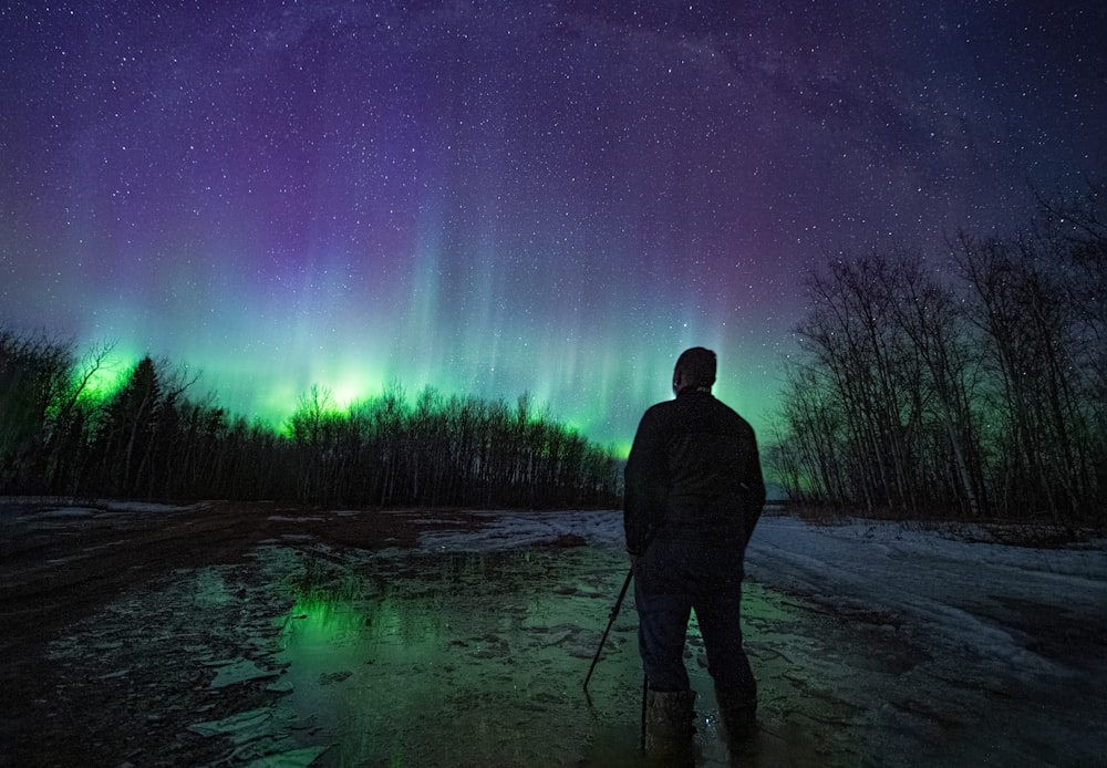 a person standing in a snowy field with a bright light in the sky