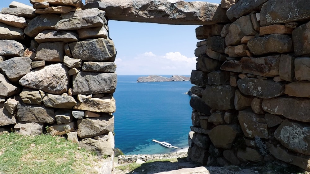a view of the ocean through a stone wall