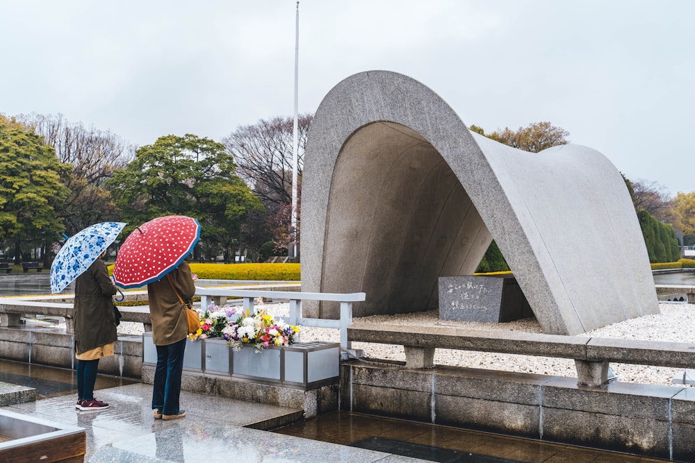 a couple of people stand near each other holding umbrellas