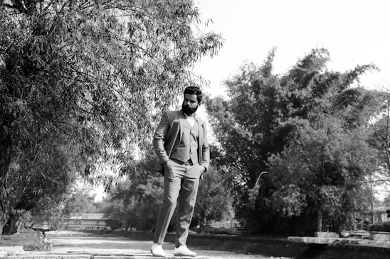 A portrait of a confident man in a suit, smiling warmly in an outdoor setting.