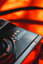 A close-up of a camera featuring the words '5 Million' with stars above it, against a vibrant orange background. The focus is on the brand text and stars, with a contrasting and warm color scheme adding emphasis.