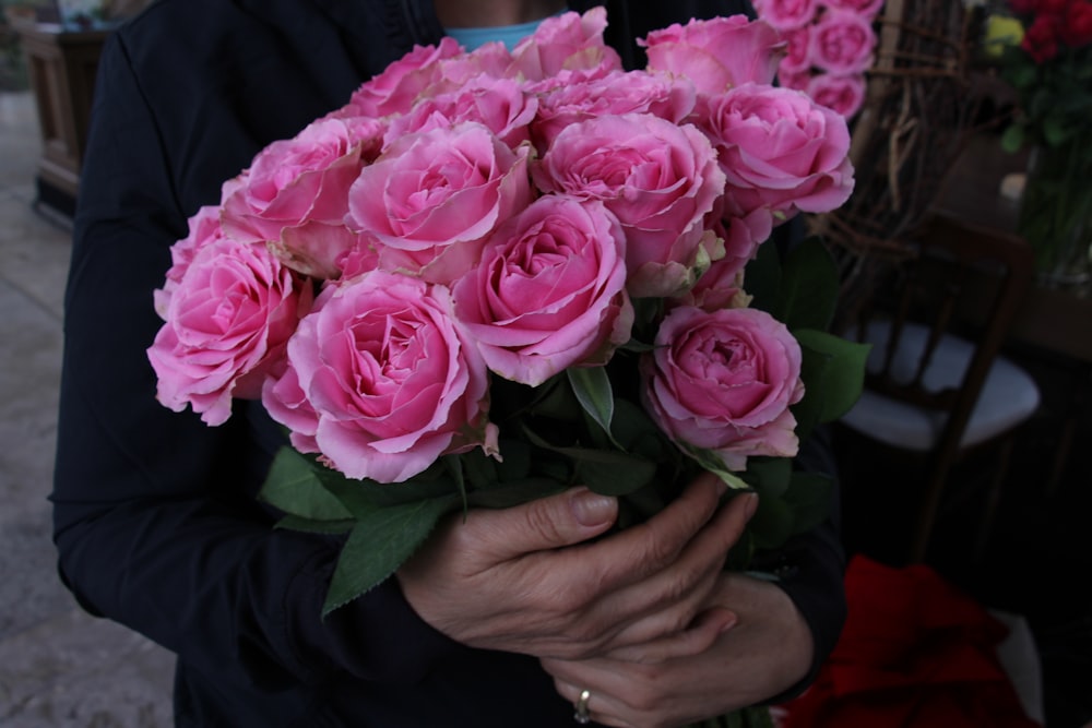 a person holding a bouquet of pink flowers