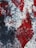 A vibrant abstract painting with swirling textures. The image features a mix of red, black, and white colors, creating a dynamic and intense visual effect. The brush strokes and patterns appear fluid and somewhat chaotic, suggesting movement and emotion.