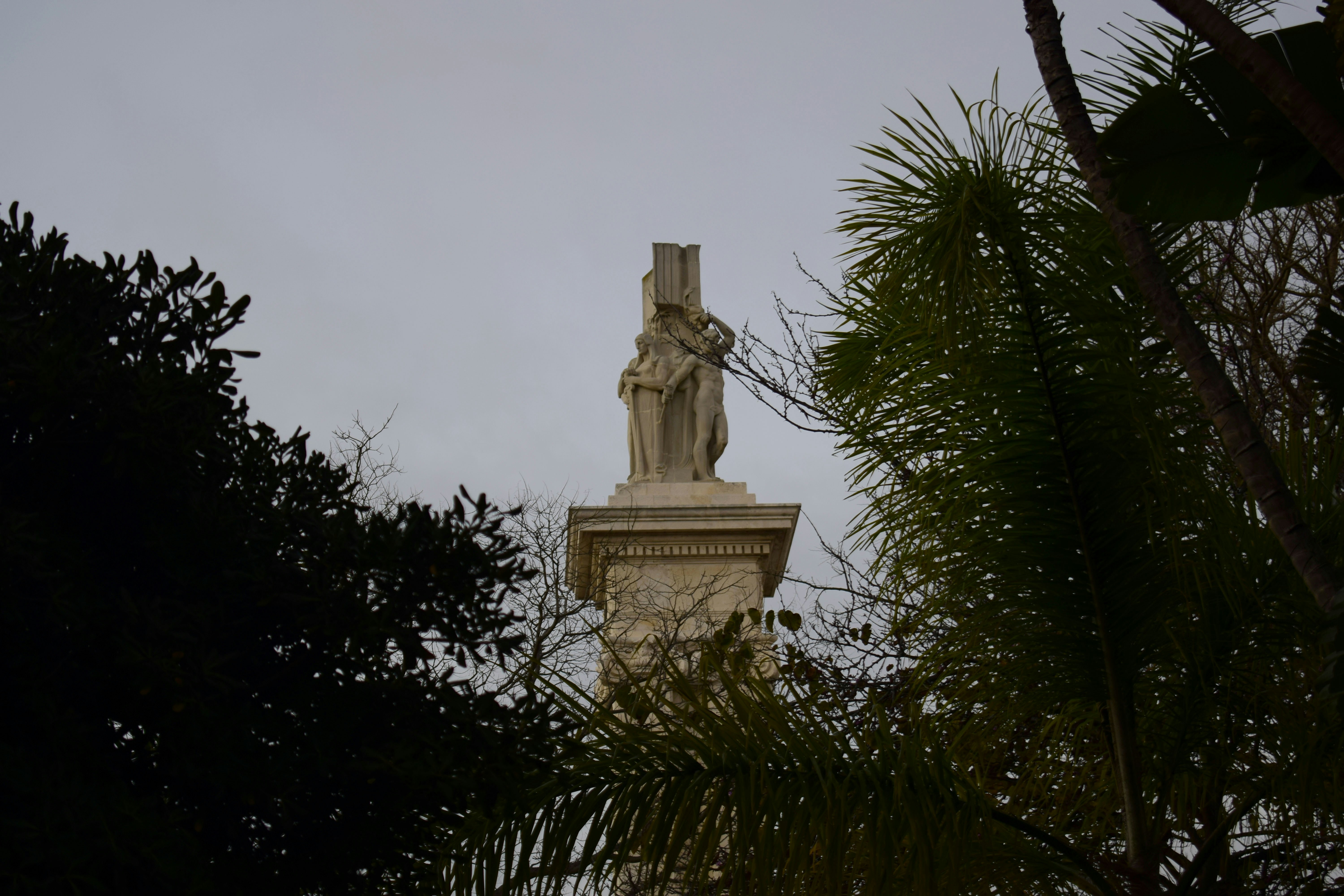 a statue on a pedestal surrounded by trees