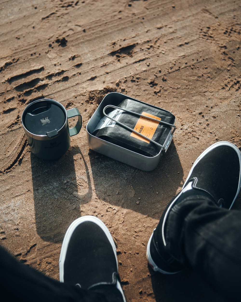 a person standing on a sandy beach with a broken can and a broken can