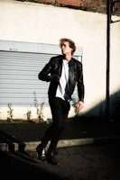 Side profile of a model in a sleek black bomber jacket walking through urban alleyways.