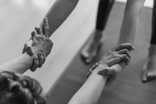 A close-up of hands joining in support during a group therapy session at the addiction treatment center.