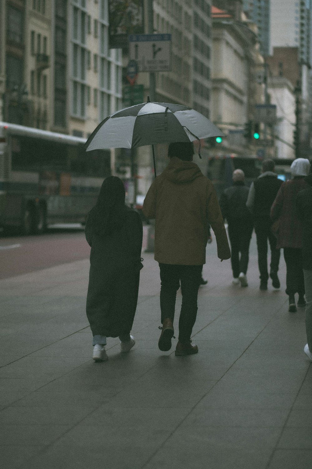 a couple walking down a sidewalk with an umbrella