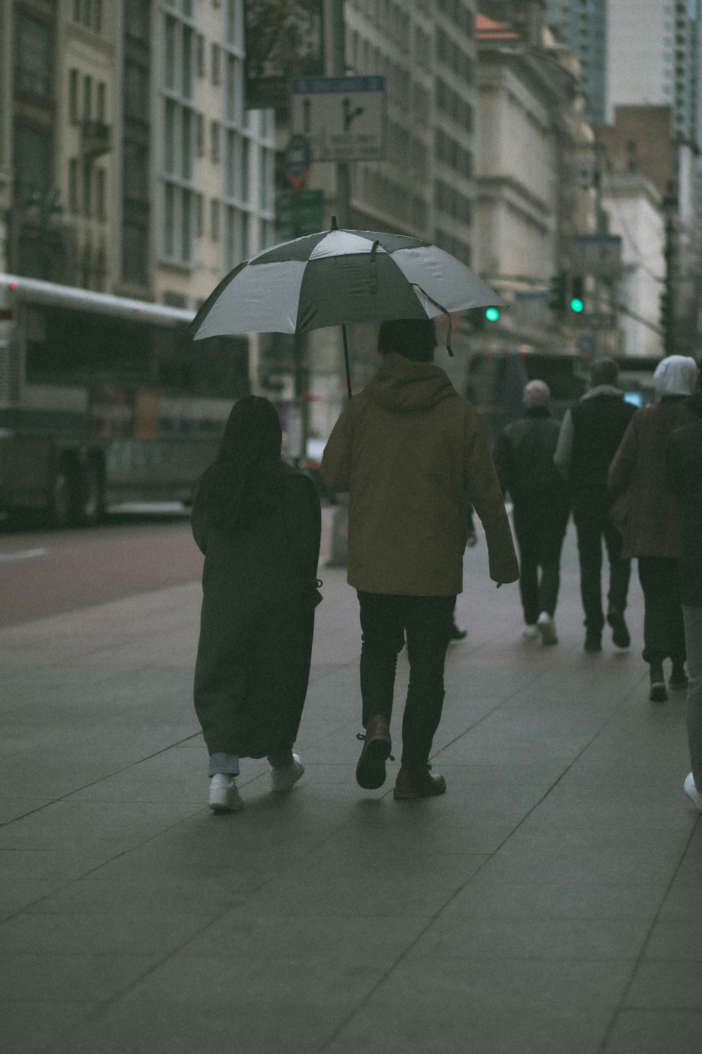 Un couple marchant sur un trottoir avec un parapluie