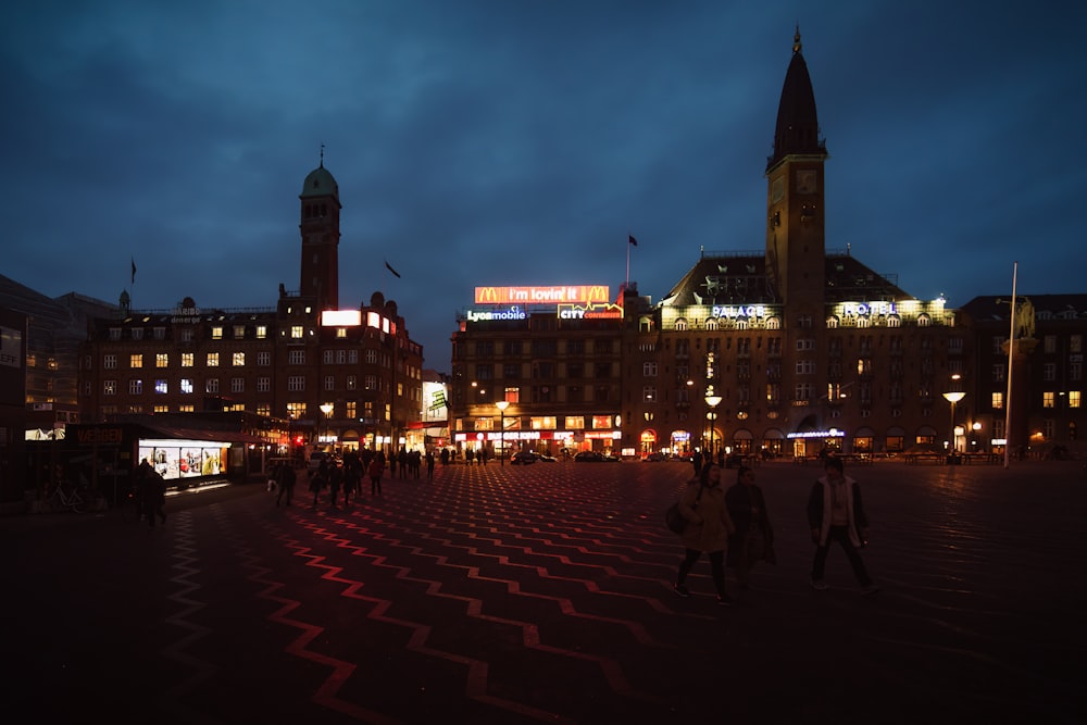 a group of people walking in a plaza with buildings in the background