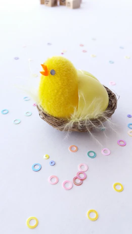 A vibrant 3D printed chook toy in bright yellow sitting on a cozy wooden shelf.
