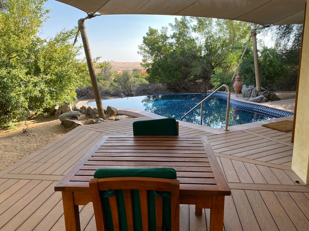 a wood deck with a pool and trees and a deck with a slide