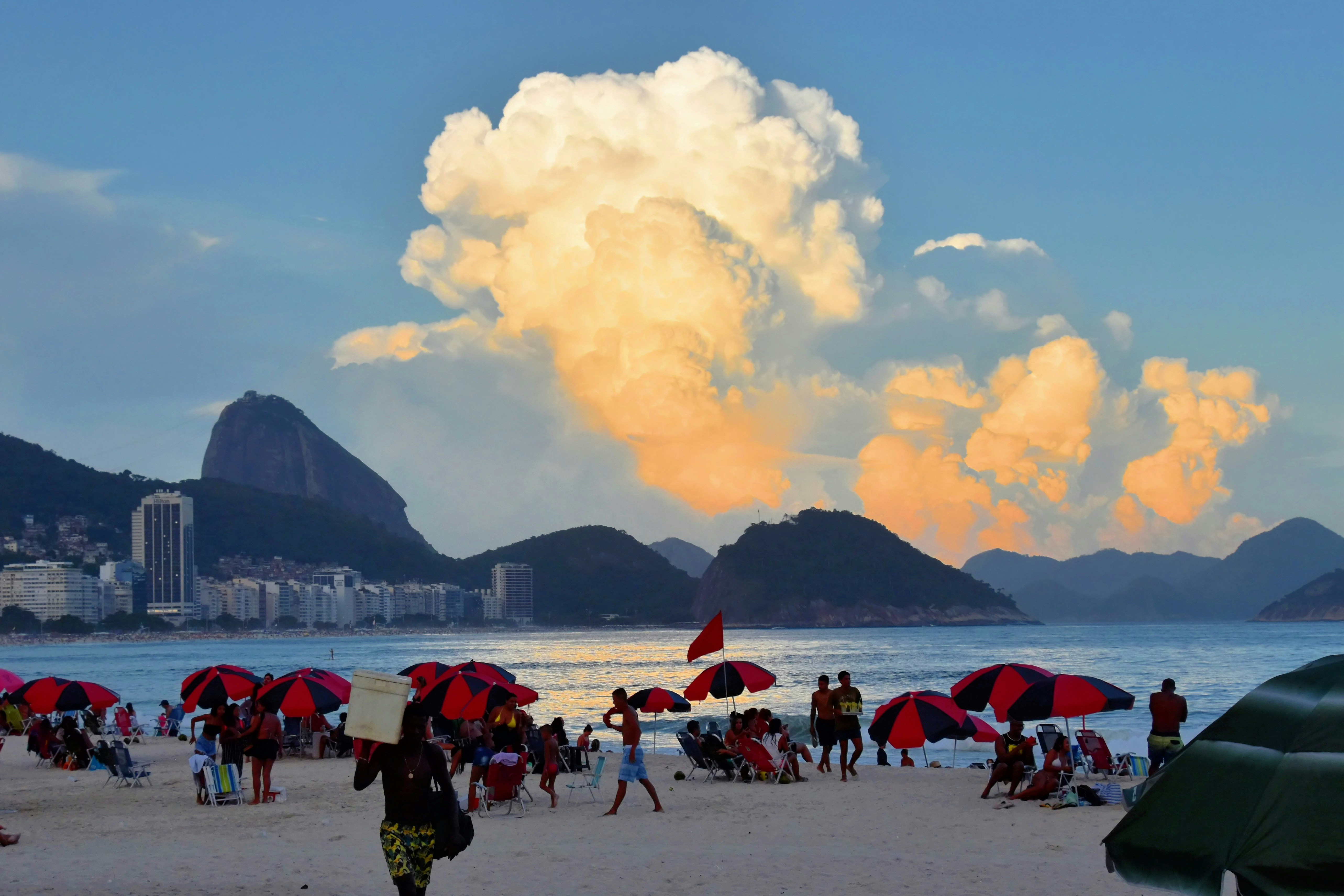 a large group of people at a beach with umbrellas