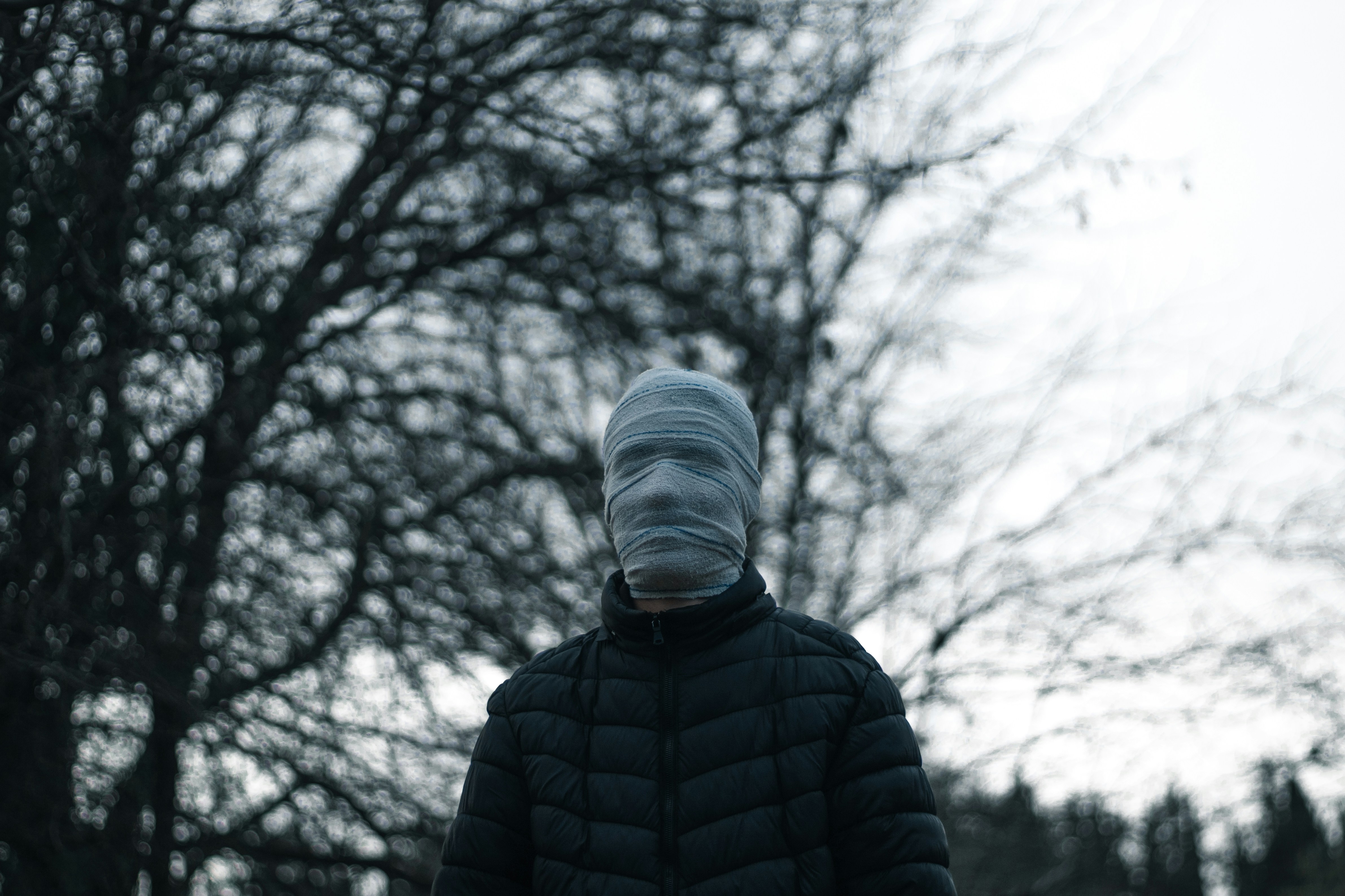 a person wearing a hoodie and standing in front of trees