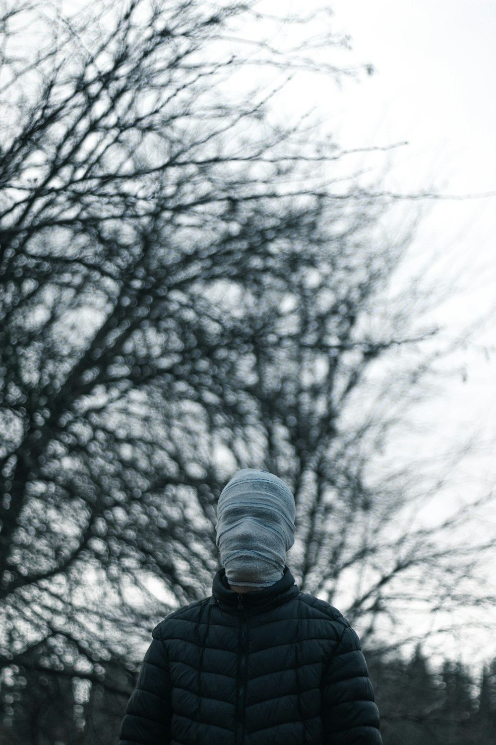 a person wearing a hoodie and standing in front of a tree