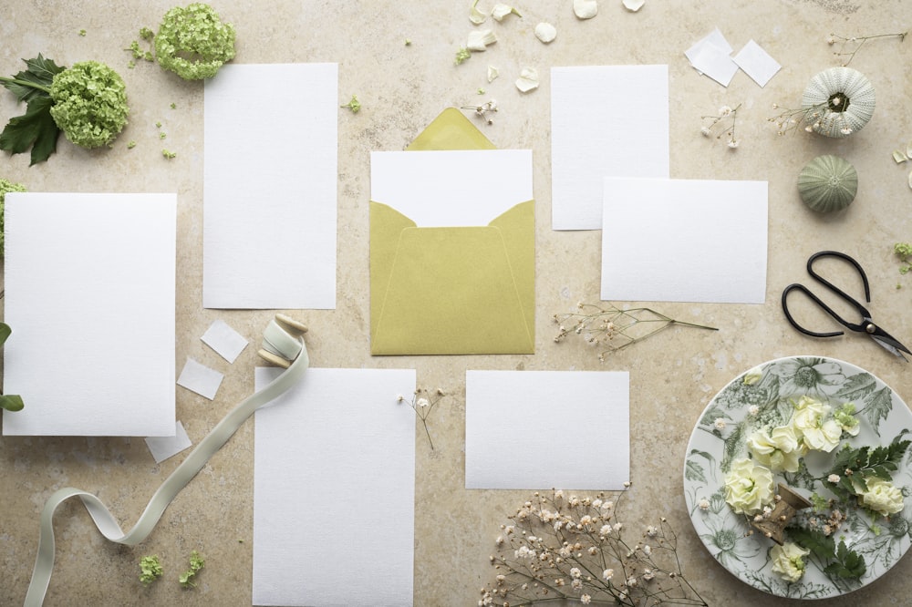 a table with white paper and a bowl of flowers