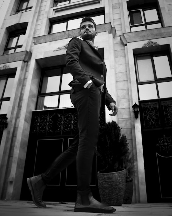 Sharp-dressed man in a tailored black suit walking confidently on a city street