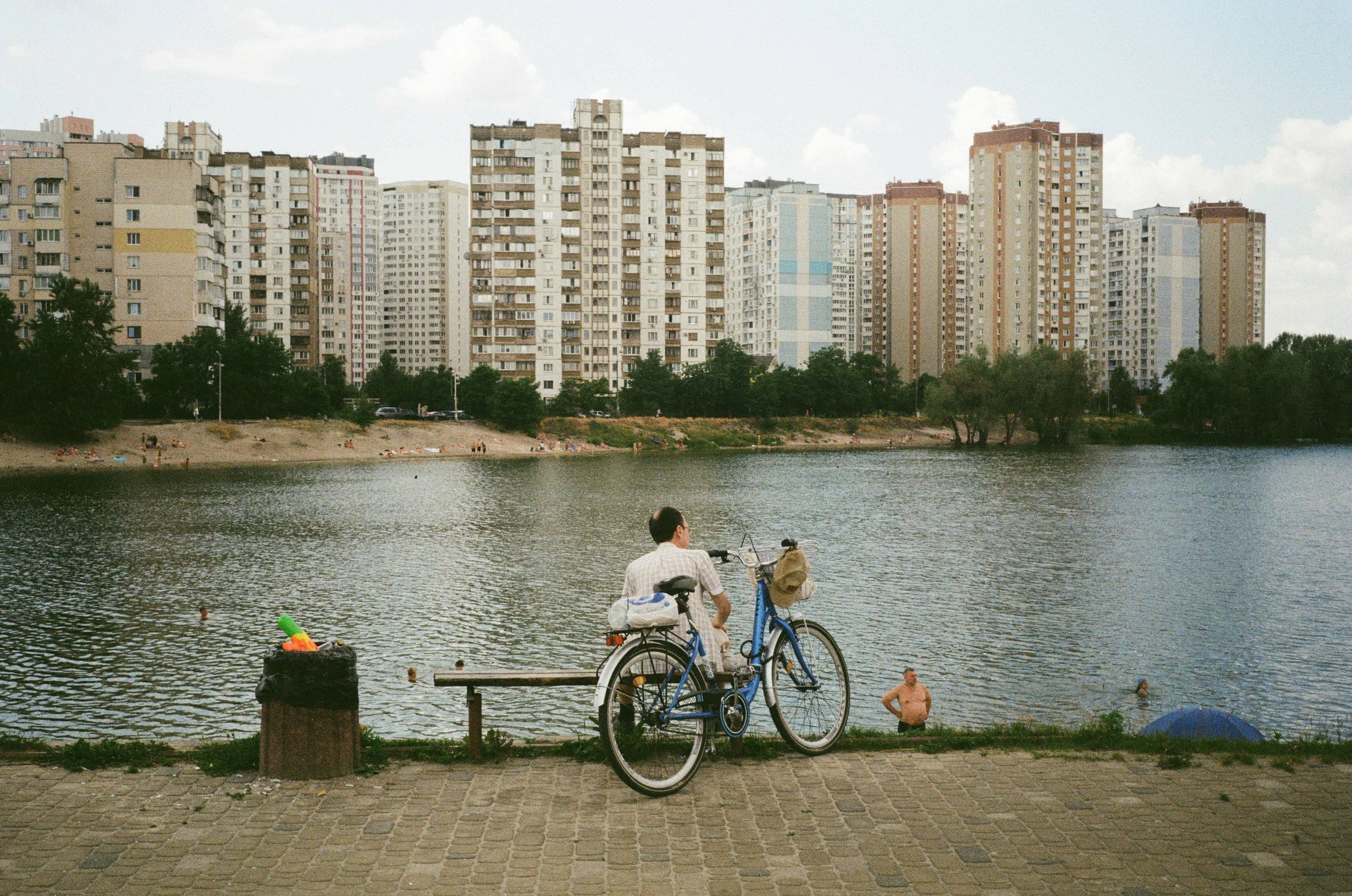 people enjoying the lake near a modern apartment building - apartments by the lake