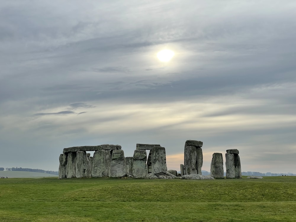 a stone structure in a field with Stonehenge in the background