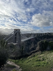 A sturdy suspension bridge spanning a deep river gorge under a bright blue sky.