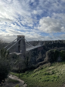 A sturdy suspension bridge spanning a deep river gorge under a bright blue sky.