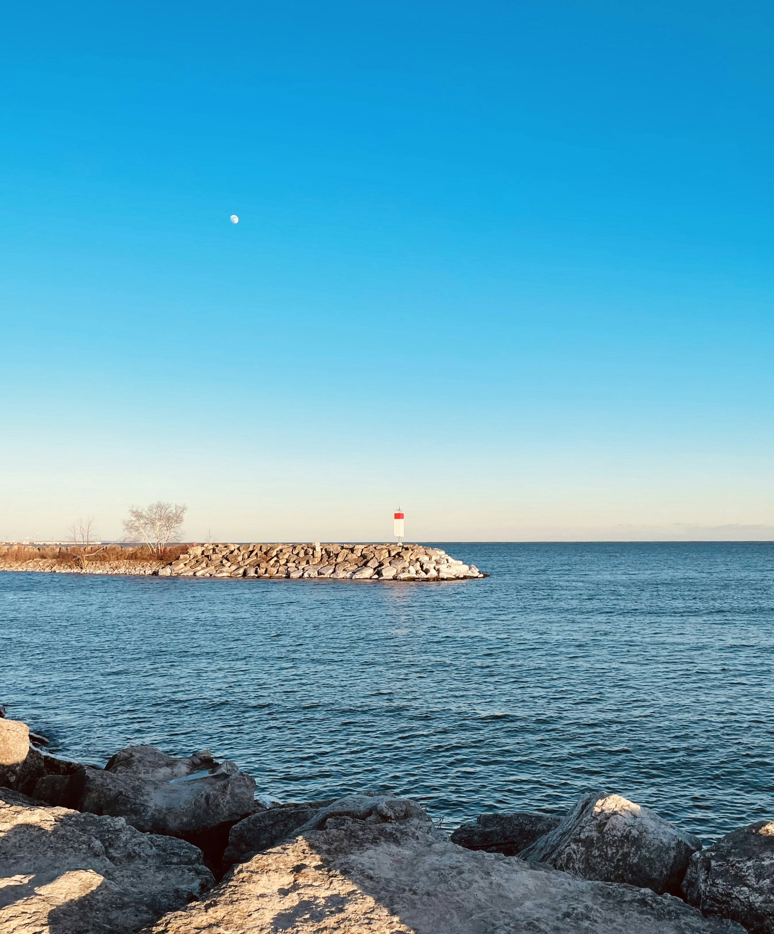 Ein felsiger Strand mit einem Leuchtturm in der Ferne