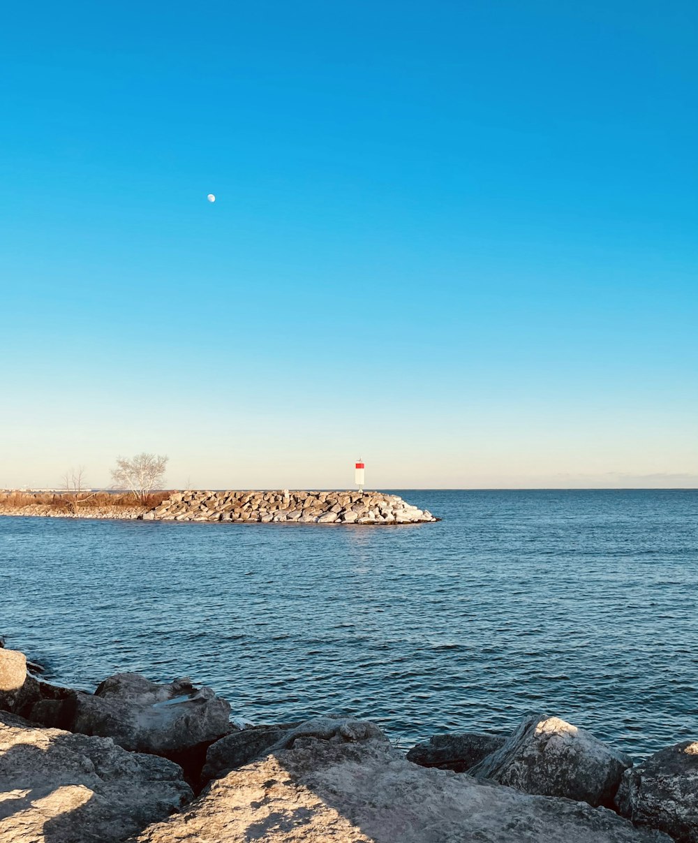 a rocky beach with a lighthouse in the distance