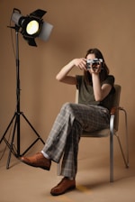 a person sitting in a chair holding a camera up to the face