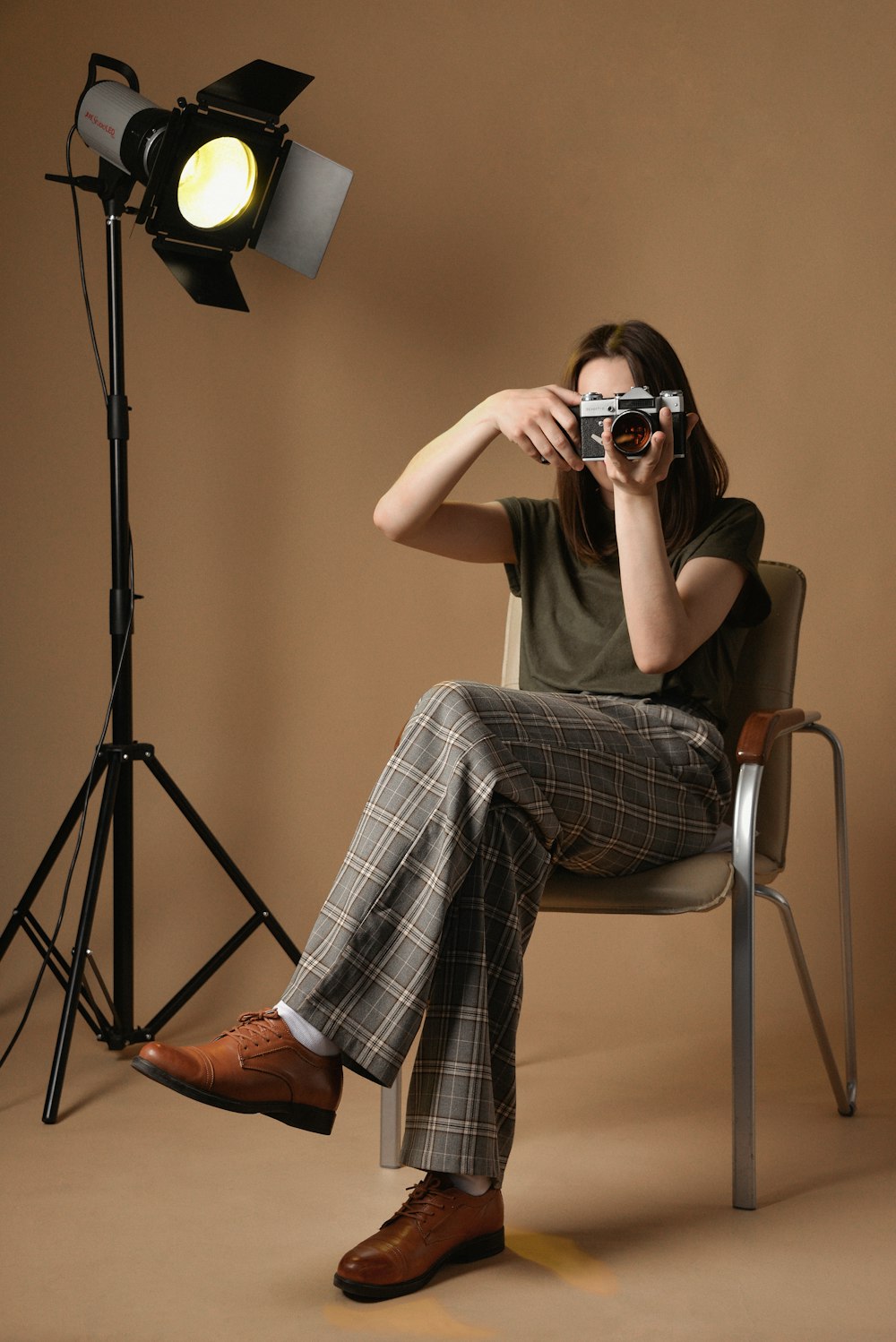 a person sitting in a chair holding a camera up to the face